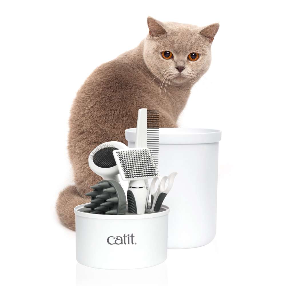 Eine Katze steht hinter dem geöffneten "Catit Kurzhaar-Pflegeset".