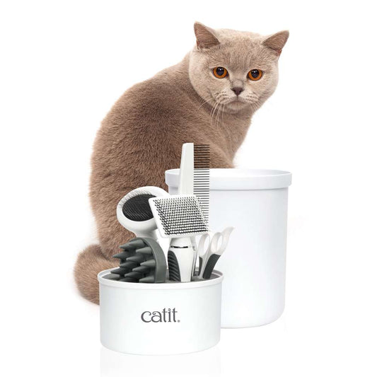 Eine Katze steht hinter dem geöffneten "Catit Kurzhaar-Pflegeset".