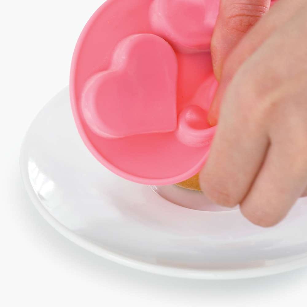 Eine Hand drückt die gefrorene Leckerli-Creme aus der Eiscreme-Form heraus.